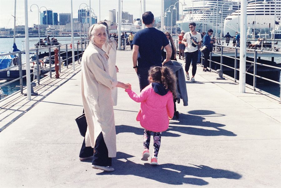 Grandmother and child on a harbor pier with cruise ships behind