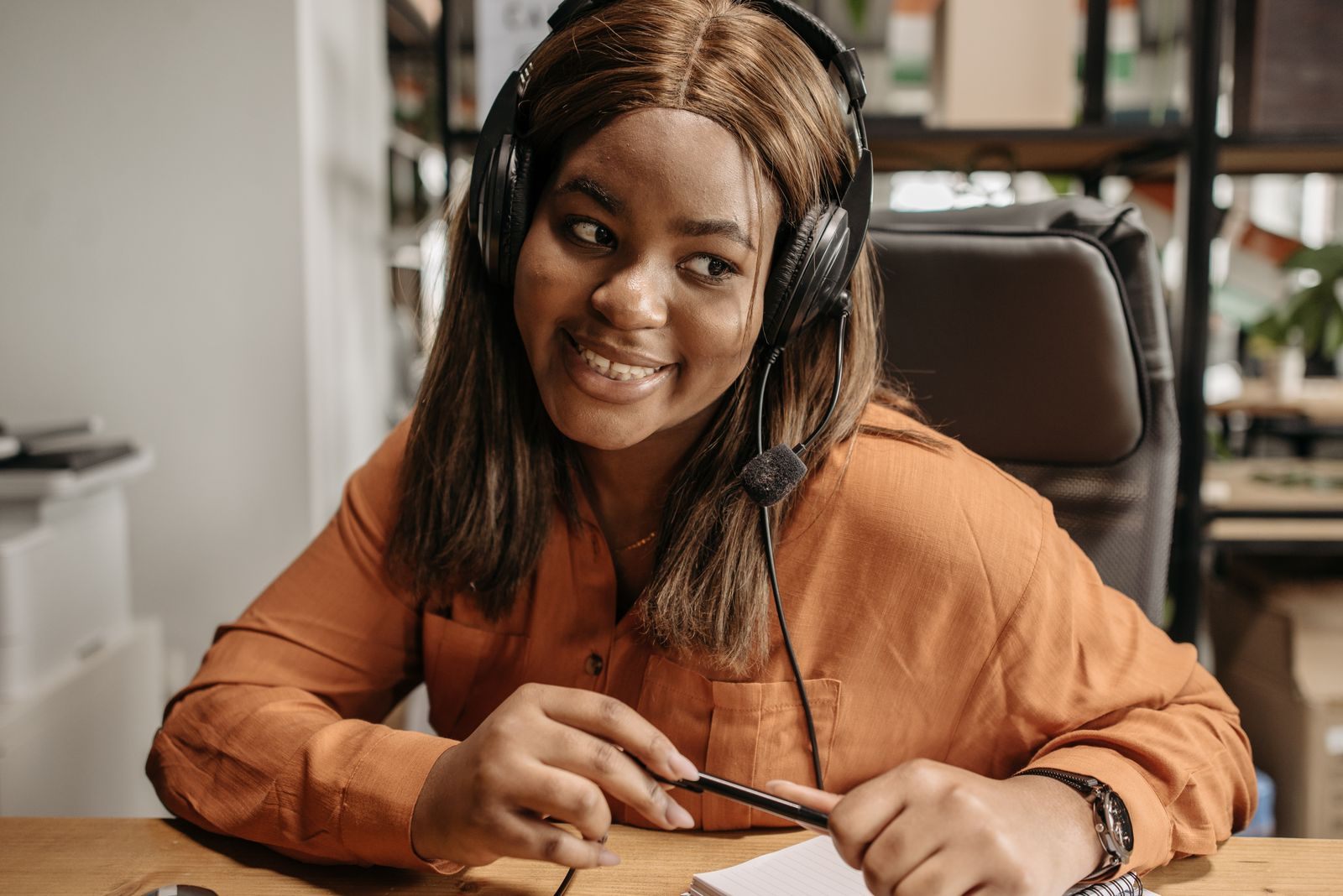 Smiling advisor wearing a headset taking notes on a client call, putting cruise selling tips to work